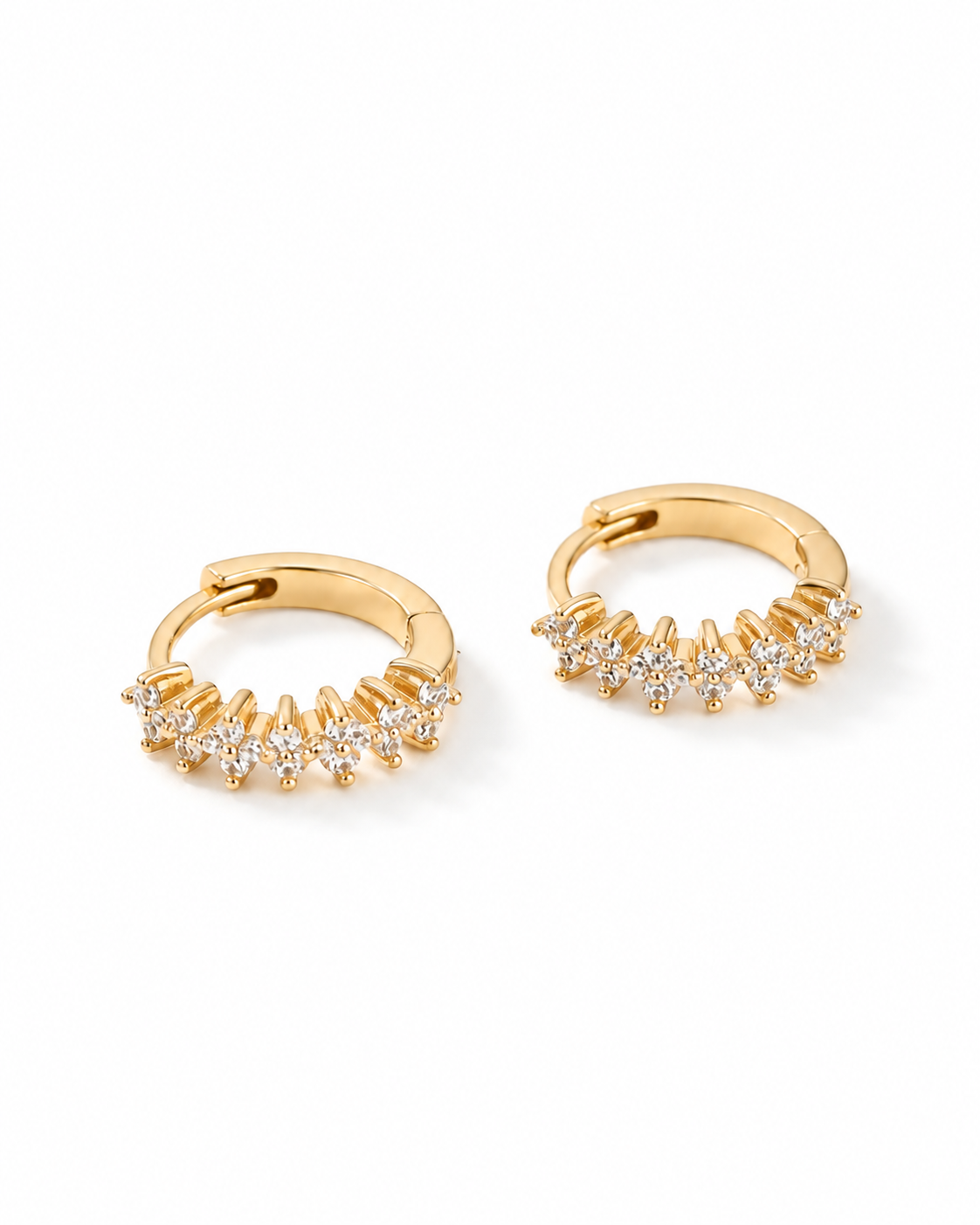 A pair of gold huggie hoop earrings embellished with small clear stones along the front, displayed on a clean white background.